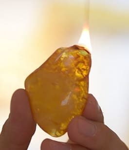 Ein Stück Bernstein brennt mit rußender Flamme.