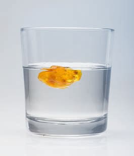 Bernstein schwimmt in einem Glas mit Salzwasser.
