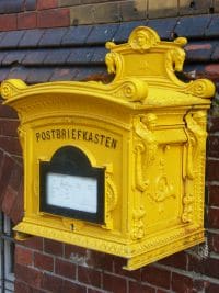 Ein gelber nostalgischer Briefkasten an einer Backsteinwand.