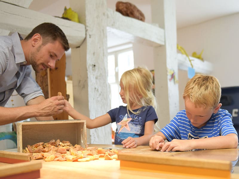 Werkstatt – Schleifen des Bernsteins Ein Kind schleift einen Bernstein in der Werkstatt.